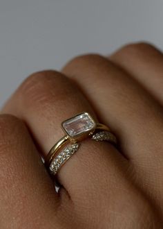 a woman's hand wearing a gold ring with an emerald and diamond set in the middle