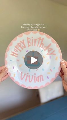 two hands holding up a happy birthday plate