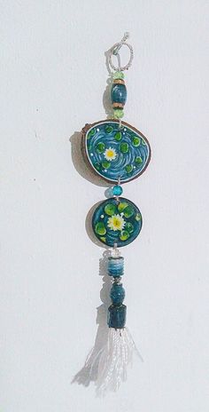 a blue and green glass wind chime hanging from a hook on a white wall