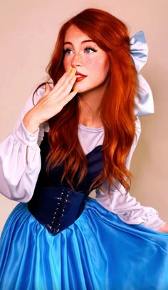 a woman with red hair wearing a blue dress and holding something in her mouth while posing for the camera