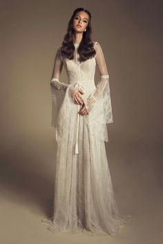 a woman in a white dress with long sleeves and lace on her arms is posing for the camera