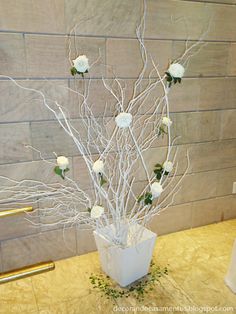 a white vase filled with flowers sitting on top of a counter next to a wall