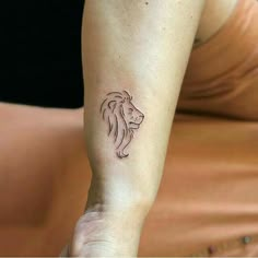 a woman's arm with a small tattoo of a lion on the left wrist