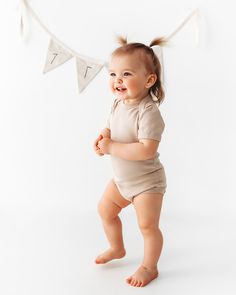 a baby standing in front of a bunting banner