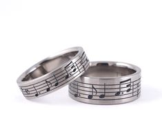 two wedding rings with musical notes on the inside and outside, set against a white background