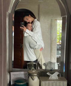 a woman taking a selfie in front of a mirror next to jars and baskets