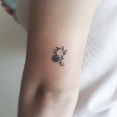 a woman's arm with a small flower tattoo on the left side of her arm