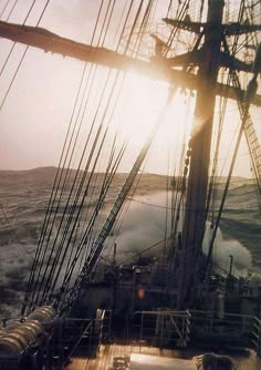 the sun shines brightly through the sails of a ship in choppy water as it moves across the ocean