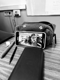 a cell phone sitting on top of a wooden table next to a bag and pen