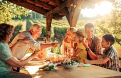 a group of people sitting around a wooden table with food and wine glasses on it