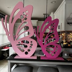 two pink butterfly sculptures sitting on top of a counter in a kitchen next to stools