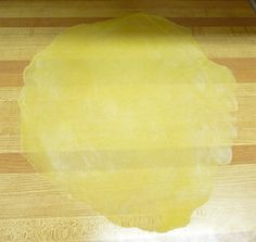 a wooden cutting board topped with yellow dough