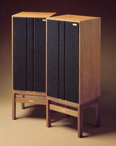 two wooden speakers sitting side by side on top of each other in front of a brown background