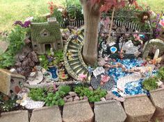 a fairy garden with lots of rocks and plants in it, including a spiral staircase leading up to a tree