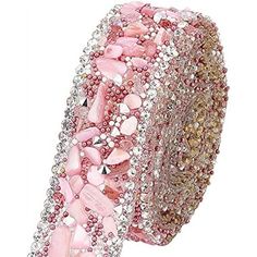 a pink and white bracelet with lots of stones on it's side, in front of a white background