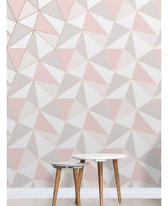 two small tables sitting in front of a pink and white wall with geometric designs on it