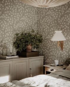 a bed room with a neatly made bed and a plant on top of the dresser