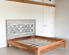 a wooden bed frame with an intricate design on the headboard and foot board, in a white room