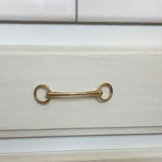 a golden metal handle on a white drawer