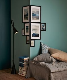 a bed sitting in a bedroom next to a wall with pictures on it and a lamp