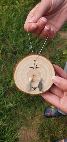 a person holding a wooden ornament with stones on it's side in their hand