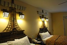 two beds in a hotel room with lamps on the wall