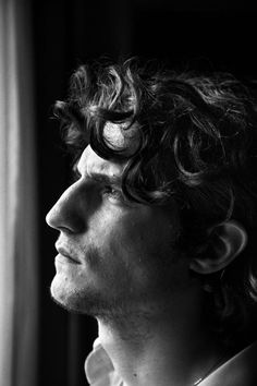 a black and white photo of a man with curly hair looking off into the distance