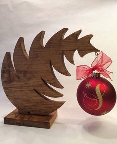 a wooden ornament with a red ribbon hanging from it's side, next to a christmas tree decoration