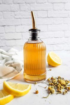 a glass bottle filled with liquid next to sliced lemons