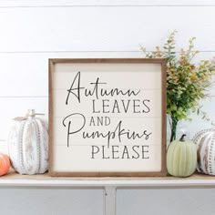 a sign that says autumn leaves and pumpkins please on top of a shelf next to flowers