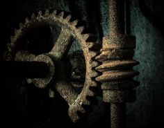 an old rusty clock with gears attached to it's sides in a dark room