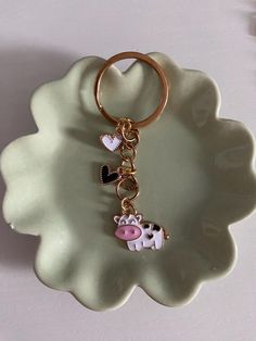 a cow keychain is sitting on a plate with a heart and two hearts attached to it