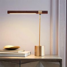 a desk lamp sitting on top of a wooden table next to a stack of books