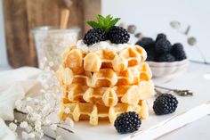 a stack of waffles topped with whipped cream and blackberries