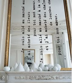 an ornate fireplace mantel topped with white vases and a large framed art piece