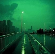 an empty walkway in the middle of a body of water with lights on at night