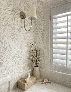 a vase with flowers sitting next to a window in a room that has blinds on the windowsill