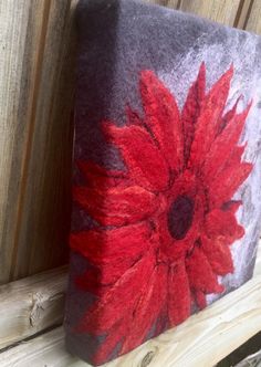 a red flower is painted on a gray and white block with wood slats behind it