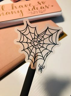 a pen with a spider web on it sitting next to a notebook and some books