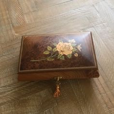 a wooden box with flowers painted on the lid and tassels attached to it