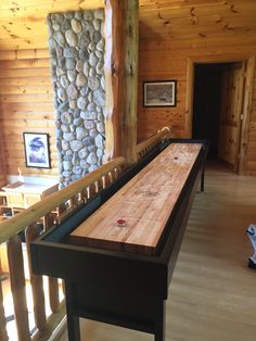 a large wooden table sitting in the middle of a living room next to a stone wall