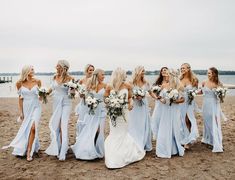 a group of women standing next to each other on top of a sandy beach near the ocean