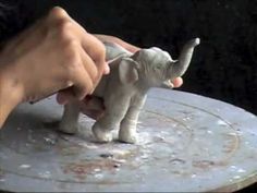 a small elephant being held by someone's hand on top of a round table