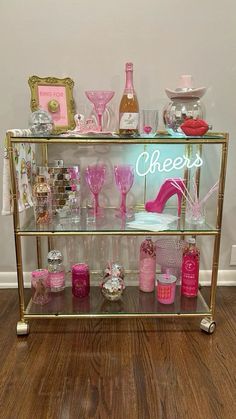 a display case filled with lots of pink and gold items on top of a hard wood floor