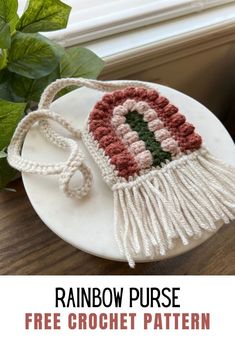 a crocheted purse sitting on top of a white plate next to a green plant