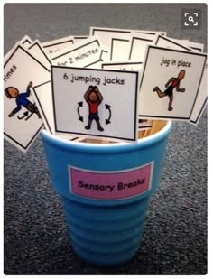 a cup filled with cards sitting on top of a table next to a blue bucket