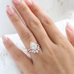 a woman's hand with a diamond ring on top of her finger and the other hand holding an engagement ring