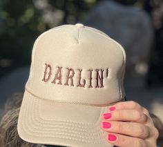 Add a touch of Southern sweetness to your style with our embroidered hat featuring the word 'DARLIN'  embroidered with a western script.  This classic sand-beige colored trucker cap is perfect for anyone who loves Southern charm and effortless style with colors ready for fall! Whether you're heading to a music festival, a day out with friends, or simply want to express your playful side, this hat is a must-have accessory. Details: Colors Available: Sand (Beige), Black, Gray Material: Polyester Foam Front truck cap with Mesh Back adjustable straps Size: One size fits most (adjustable strap) Embroidery: machine embroidered by me using high quality thread   Style: Otto foam trucker cap with a splash of western charm.     Pricing:$25 Shipping:$2 *Processing Time: 1 -2days *Shipping Time: 3-5 b Adjustable Fall Trucker Hat With Curved Brim, Adjustable Curved Brim Trucker Hat For Fall, Country Style Adjustable Trucker Hat With Curved Brim, Adjustable Trucker Hat With Curved Brim For Fall, Adjustable Curved Brim Baseball Cap For Outdoor Events, Western Style Adjustable Trucker Hat 5-panel, Adjustable Snapback Trucker Hat For Country Events, Adjustable Western Style Trucker Hat, Adjustable Baseball Cap For Country Events