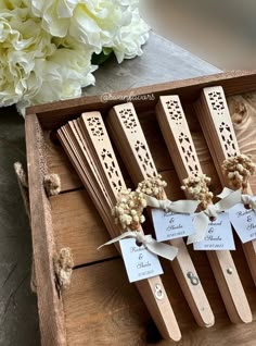 four wooden spoons with tags on them sitting in a box next to some flowers