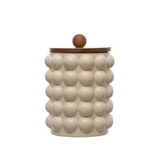 a white ceramic container with wooden lid and balls on the top, against a white background